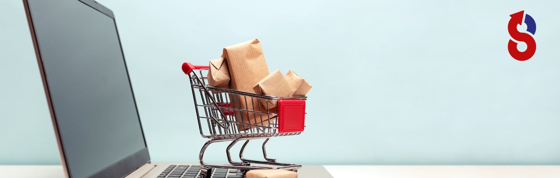 Ein kleiner Einkaufswagen voller Pakete steht auf einem Laptop, symbolisch für Onlineshop-Optimierung und digitales Einkaufen. Das Bild repräsentiert den nahtlosen Einkauf